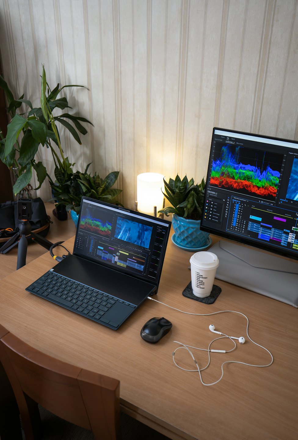 Laptop and monitor with editing software on a wooden desk.